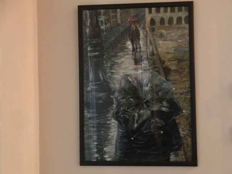 A painting by Ciorsdan Glass of a figure holding an umbrella on a Parisian street.